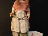 an image of a doll is standing on a stand with a card