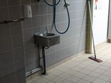 une salle de bains avec des toilettes, un lavabo et une serpillière posée par terre