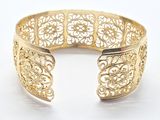 a close up of a gold cuff bracelet with intricate designs