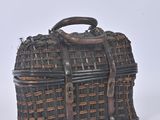 a small wicker bag with a handle on a white surface