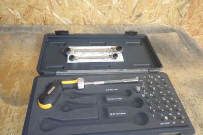 un jeu d'outils rangé dans une boîte à outils posée par terre