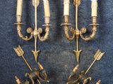 two brass wall sconces with arrows on them on a blue background