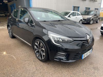 La voiture noire est garée devant un immeuble, avec d'autres voitures en arrière-plan.