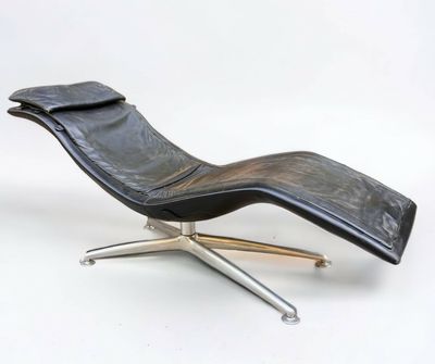 une chaise longue en cuir noir posée sur un piètement en métal