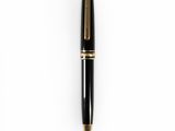 a black and gold ballpoint pen sitting on top of a white surface