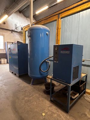 two air compressors in a room with a blue tank
