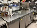 un plan de travail en acier inoxydable dans une cuisine professionnelle, sur lequel sont posés de nombreux plats