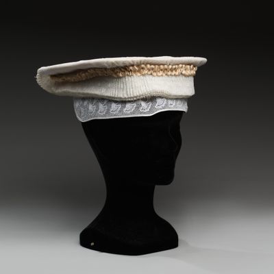 chapeau en tricot blanc et doré posé sur une tête de mannequin noire
