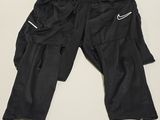 black cargo pants with zippers and pockets hanging on a wall