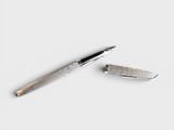 a pen and a knife laying on a white surface