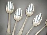 six silver spoons are lined up in a row on a gray surface