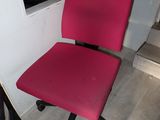 a red office chair that is sitting in the corner of a room