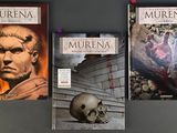 three books on a table with a skull in front of them