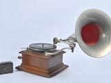 a silver and red gramphone next to a block of wood