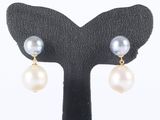 une paire de boucles d'oreilles en perles et en or, posée sur un socle noir