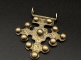 un pendentif en forme de croix en or orné de quatre boules et d'une chaîne, sur un fond noir