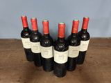 six bottles of red wine are lined up on a wooden table