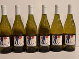 six bottles of white wine are lined up on a table