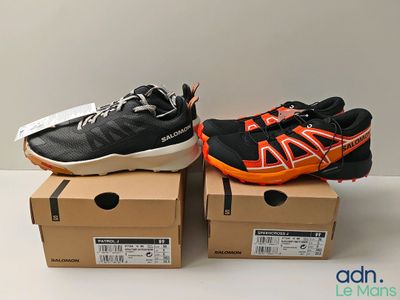 une paire de chaussures de course noires et orange posée sur une boîte en carton