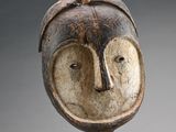 un gros plan d'un masque en bois posé sur un socle