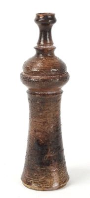 a small wooden pepper mill on a white surface