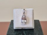 silver plated pendant with a clear crystal in a box on a marble block