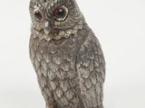 silver owl figurine sitting on a white surface