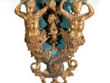 a gold and blue vase with two statues on it
