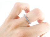 a person ' s hand holding a diamond ring on a white surface
