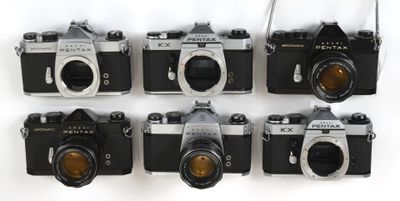 six vieux appareils photo sont alignés en rang sur une surface blanche