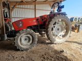 un tracteur rouge garé sur la terre battue