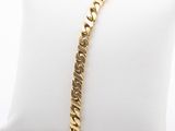 a gold bracelet on a pillow on a white pillow