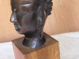 a bronze head of a woman on a wooden block