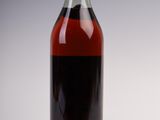 bottle of red wine sitting on a white surface with a gray background