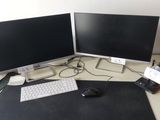 deux écrans d'ordinateur posés sur un bureau, avec une souris et un clavier