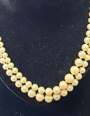 a yellow pearl necklace on a black mannequin stand