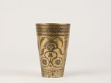 an antique brass cup with a floral design on it