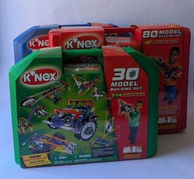 trois boîtes de jouets k ' nex sont empilées les unes sur les autres