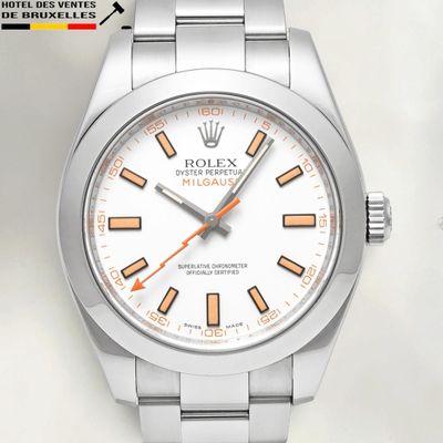 a close up of a watch with a white dial and orange hands