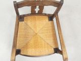 a small wooden chair with a woven seat on a white floor