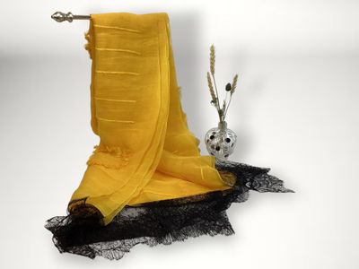 a yellow scarf hanging on a clothes rack next to a vase