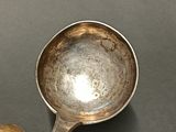 a silver spoon with a spoon handle next to a piece of bread
