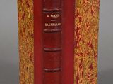 an old book with a red cover sitting on top of a table