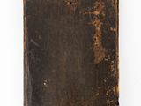 an old book is sitting on a white surface with a white background