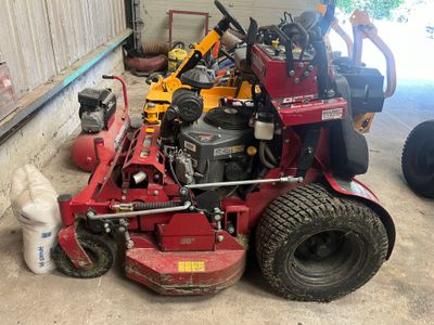 un homme debout à côté d'une tondeuse à gazon rouge dans un garage