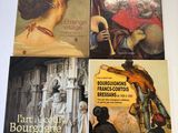 trois livres posés sur une table blanche, avec un tableau représentant une femme et un homme