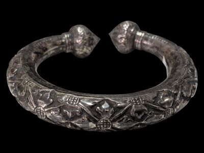 a close up of a silver bracelet on a black background