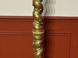 brass plated candle holder on a carpeted floor in front of a red wall