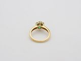 a gold ring with a green emerald stone in the center