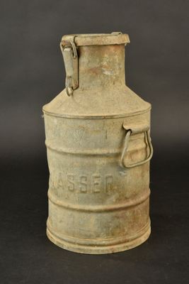 an old metal milk can sitting on top of a black table